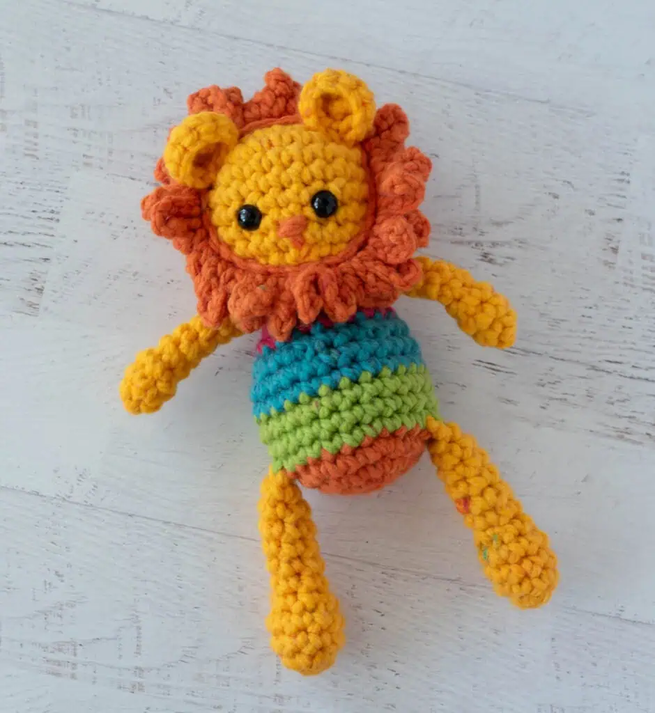 A yellow and orange rochet lion with a rainbow striped body